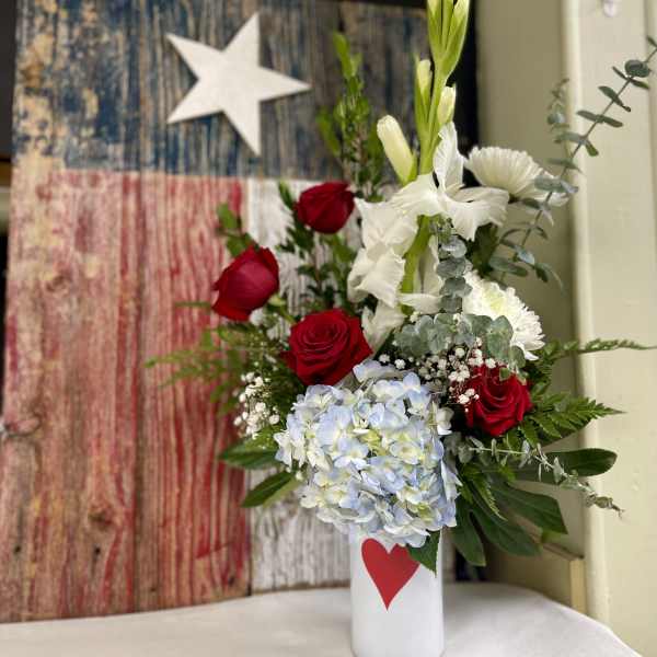 Red roses and white flowers in a white vase with a red heart