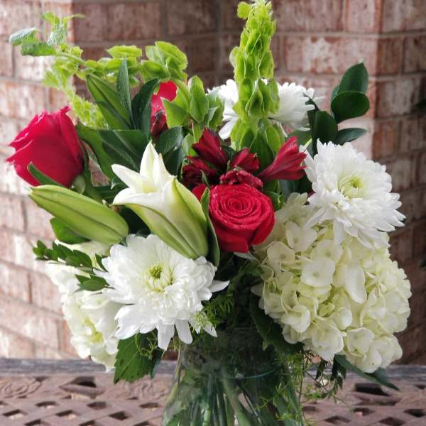 Bouquet of red roses, white lilies, and white chrysanthemums in a glass vase