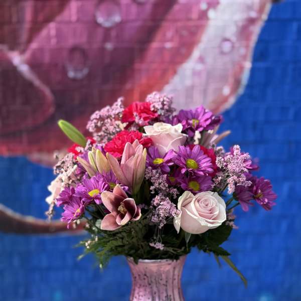 Pink and purple mixed bouquet in a pink glass vase