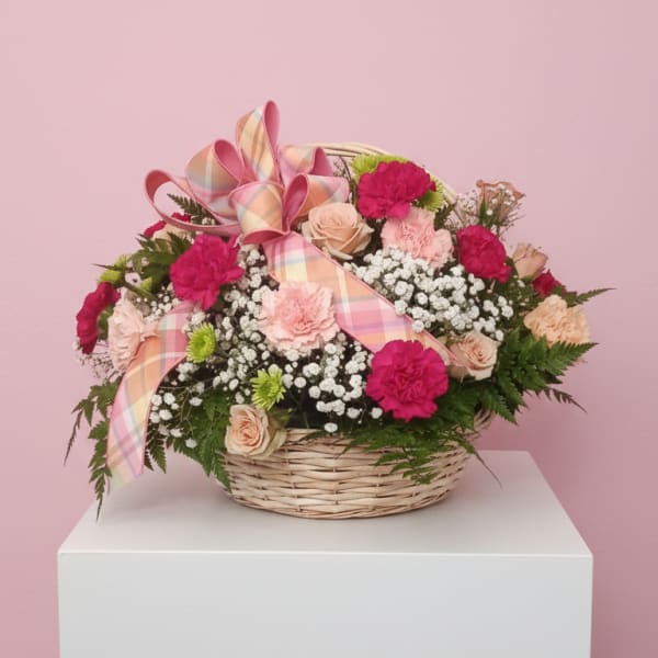 Basket arrangement of pink and peach flowers with a plaid ribbon