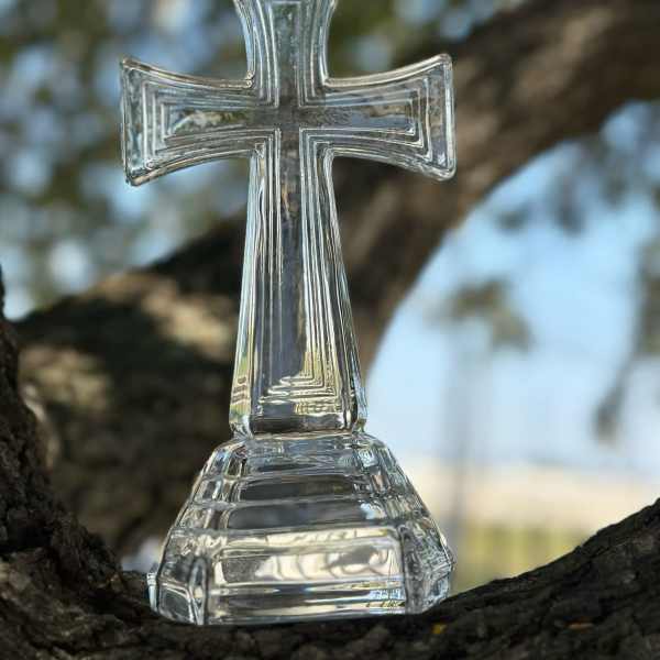 Clear glass cross ornament on a tree branch