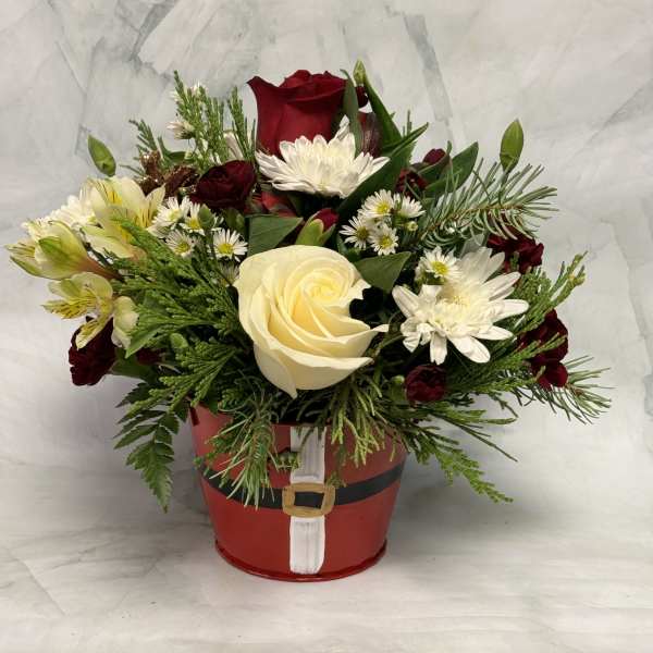Red and white flower arrangement in a Santa-themed container