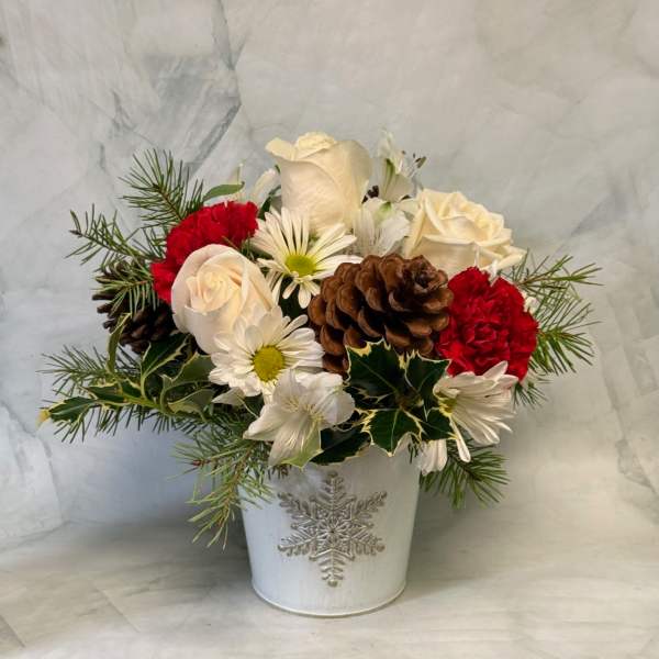 Holiday bouquet of white roses, red carnations, and daisies in a white vase
