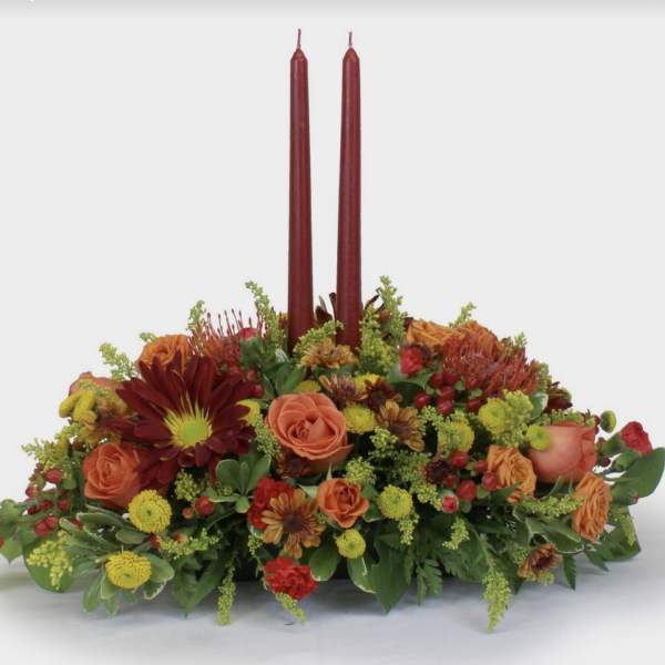 Low floral centerpiece with two burgundy taper candles