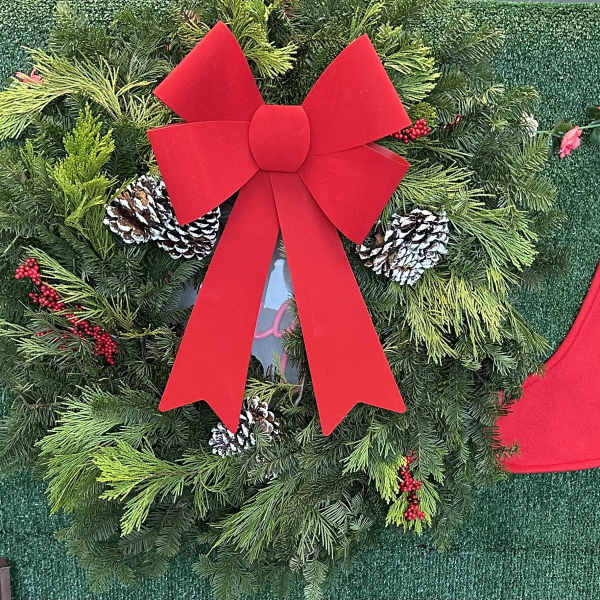 Christmas wreath with a large red bow, pinecones, and evergreen branches