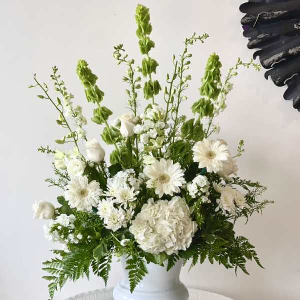White floral arrangement in a white pedestal vase