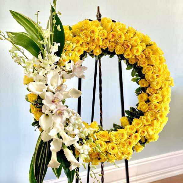 Yellow rose wreath with white orchids on a standing easel