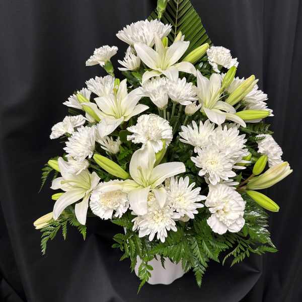 White lilies and chrysanthemums arranged in a white vase