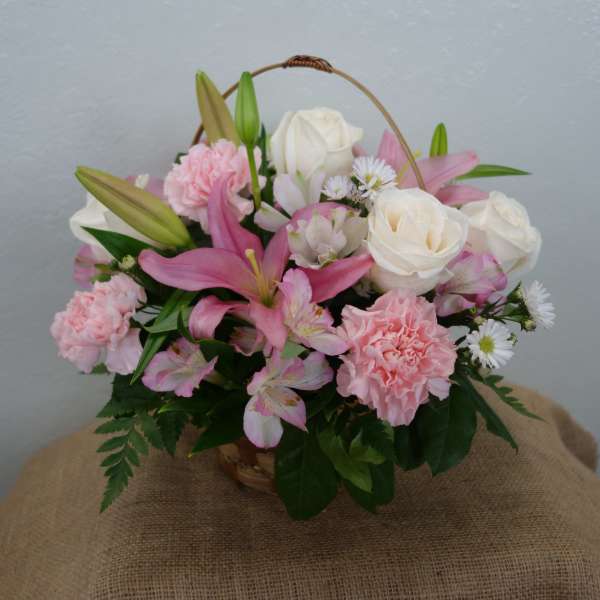 Basket arrangement of pink lilies, white roses, and carnations