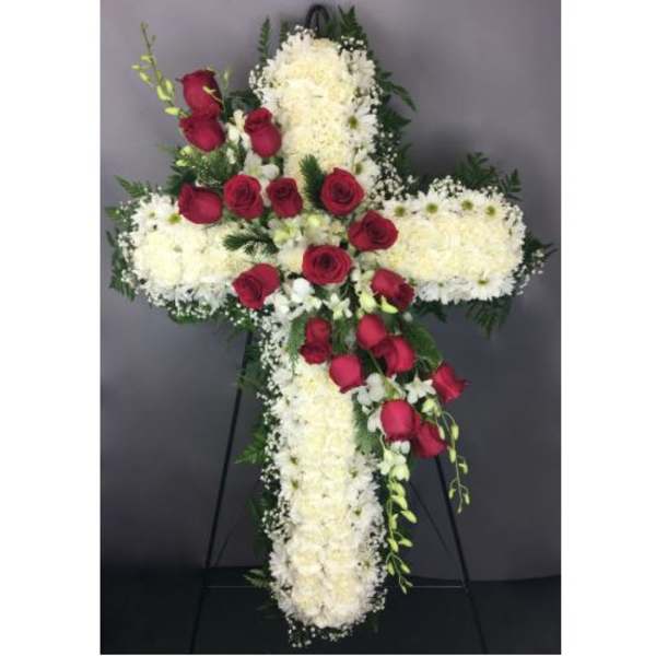 Cross-shaped floral arrangement with red roses and white flowers on an easel