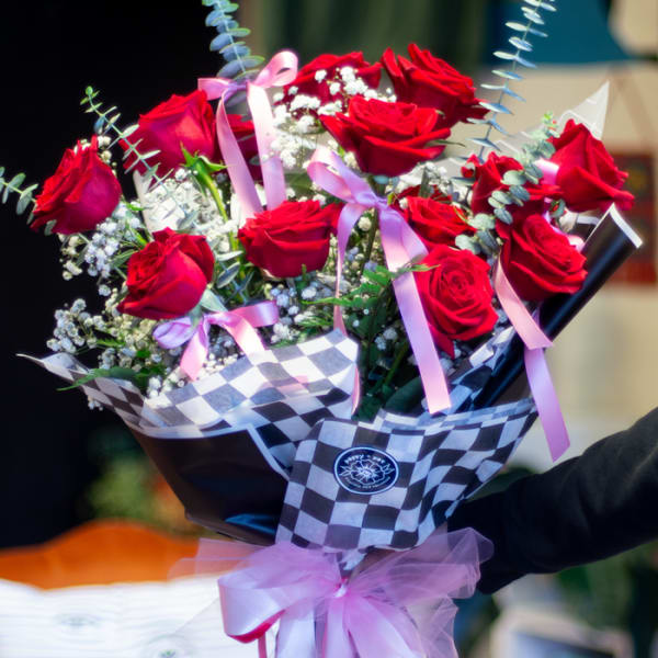 Bouquet of red roses with pink ribbons and checkered wrap