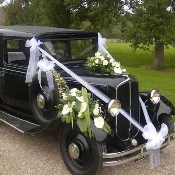 Black vintage car decorated with white ribbons and floral sprays