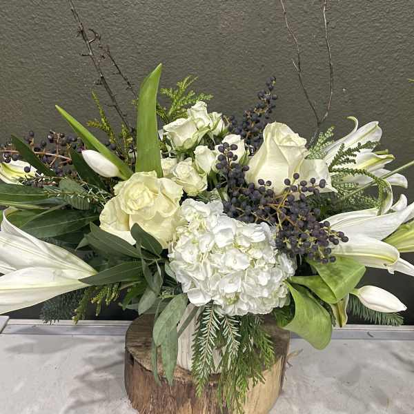 White lilies and roses arranged in a wooden vase