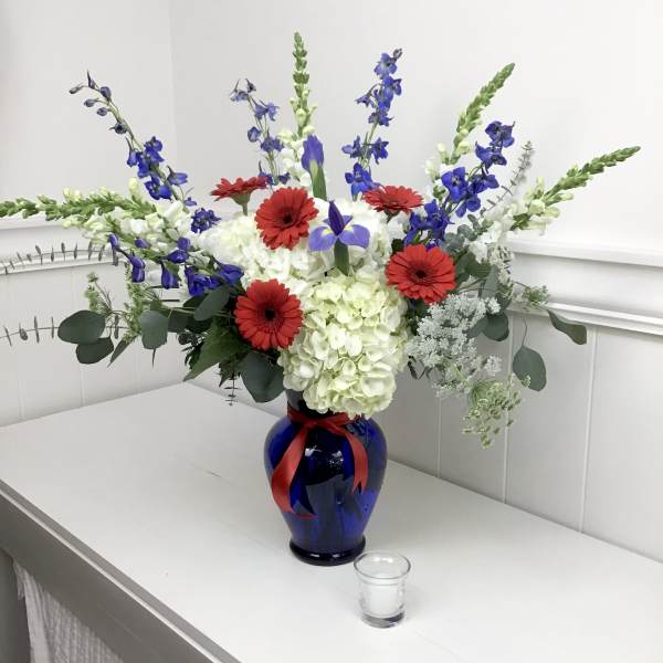 Blue vase with red gerberas, white hydrangeas, and blue delphinium