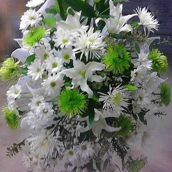 White and green funeral spray with lilies and daisies on a stand