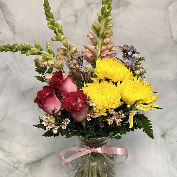 Mixed bouquet with yellow chrysanthemums, pink roses, and a glass vase tied with ribbon