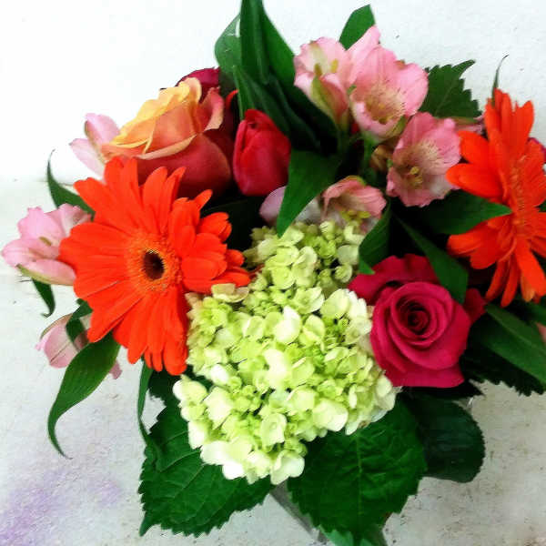 Bouquet of orange gerbera daisies, pink roses, and pale green hydrangea