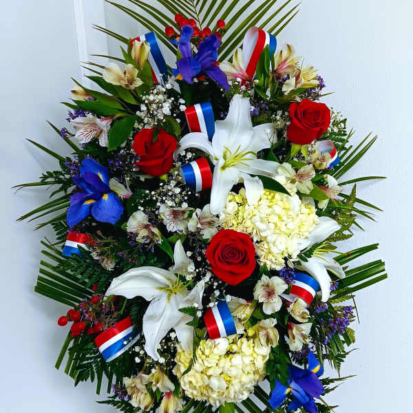 Large floral wreath with red roses, white lilies, and blue flowers