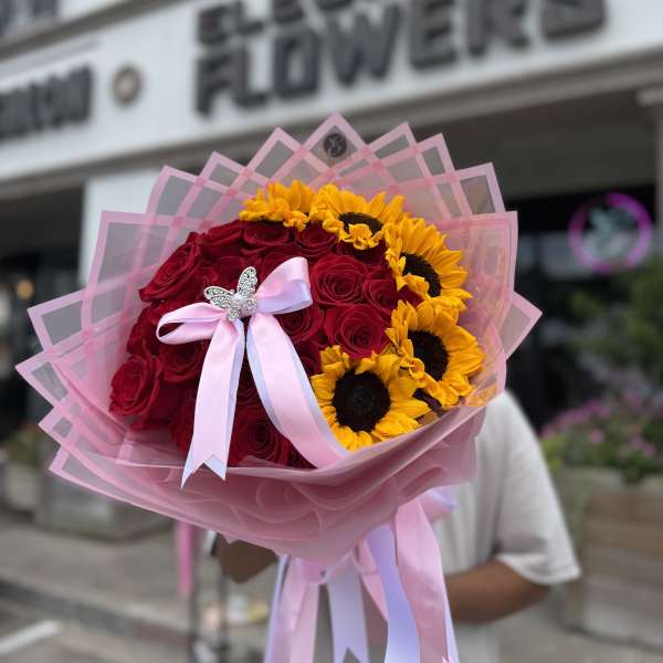 Bouquet of red roses and yellow sunflowers wrapped in pink paper