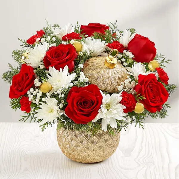 Red roses and white daisies in a gold vase with holiday ornaments