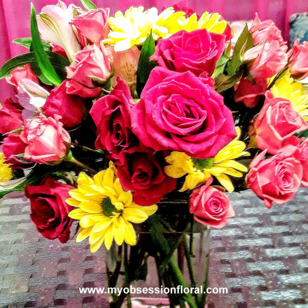 Bouquet of pink and red roses with yellow daisies in a glass vase