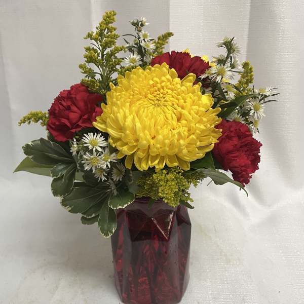 Bouquet of yellow and red flowers in a burgundy vase
