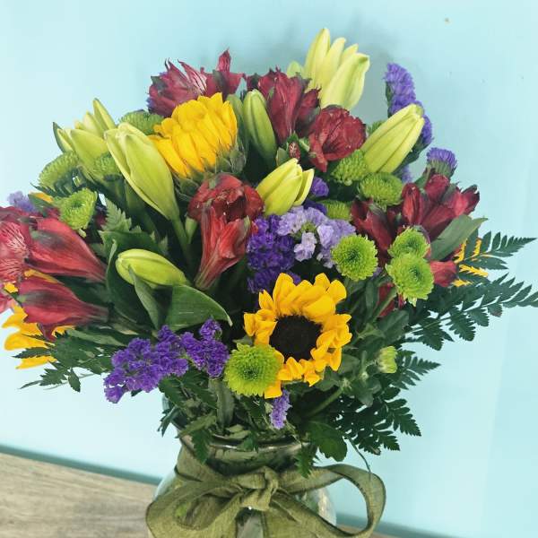 Mixed bouquet in a glass vase with yellow lilies and purple flowers