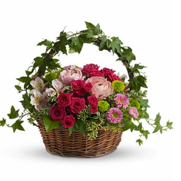 Basket of pink and red roses with mixed flowers and ivy arching over the top