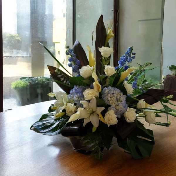 White and blue floral arrangement in a low container on a table