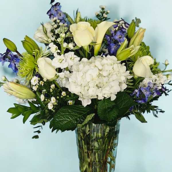 White and blue floral arrangement in a clear glass vase