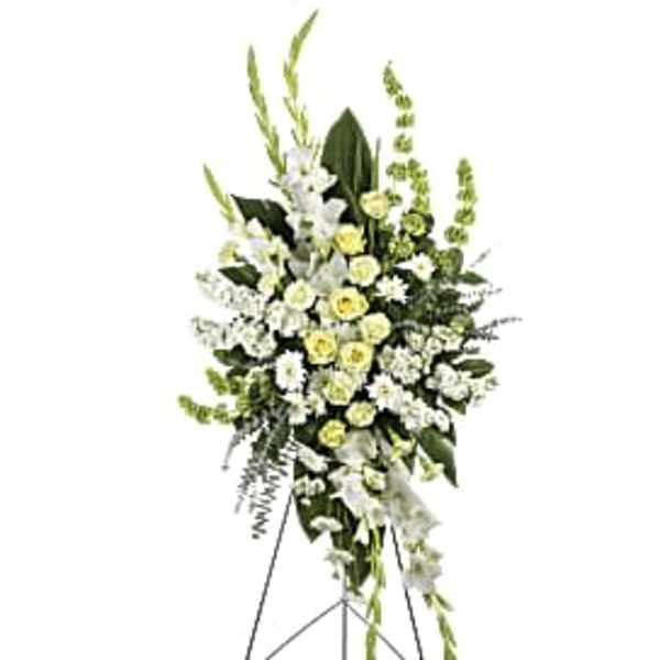 Tall white and pale yellow funeral spray on a stand