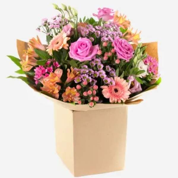 Mixed bouquet of pink and peach flowers in a tan box