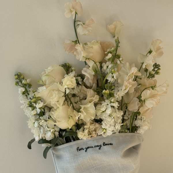 Cream floral bouquet in a light fabric wrap with handwritten text