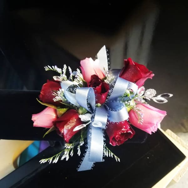 Small bouquet of red and pink roses tied with a blue ribbon