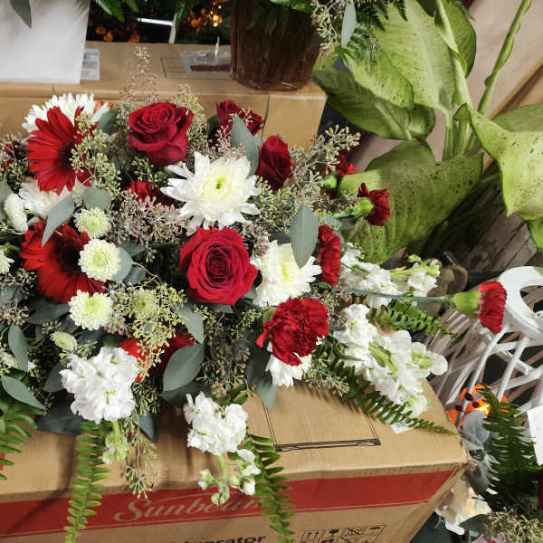 Red and white floral arrangement with roses, daisies, and carnations