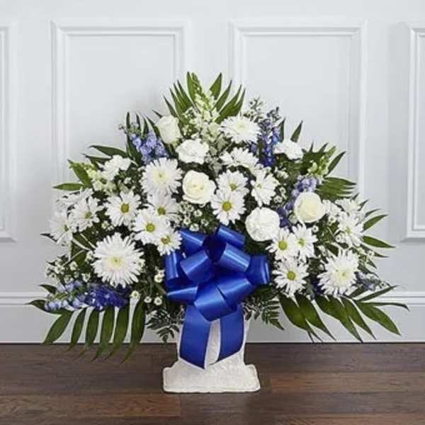 White floral standing spray with a blue ribbon on a white easel