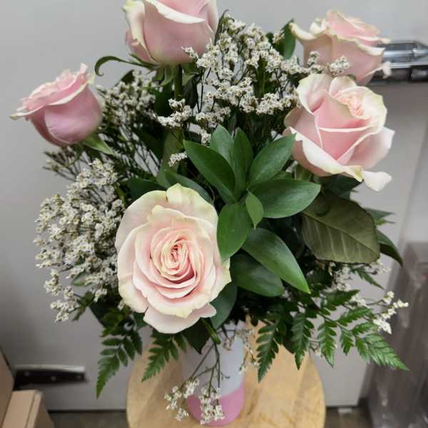 Bouquet of pale pink roses with white filler flowers in a pink vase