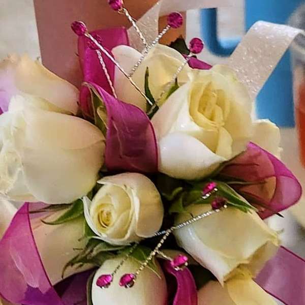 Bouquet of white and pale yellow roses with pink ribbon accents