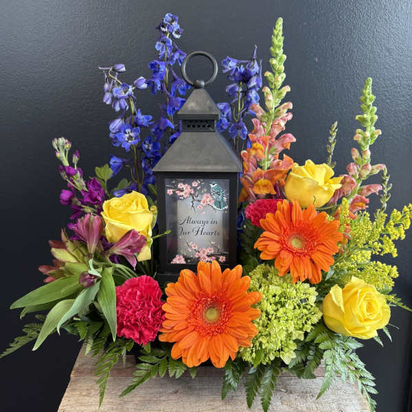 Colorful sympathy lantern arrangement with roses and gerbera daisies