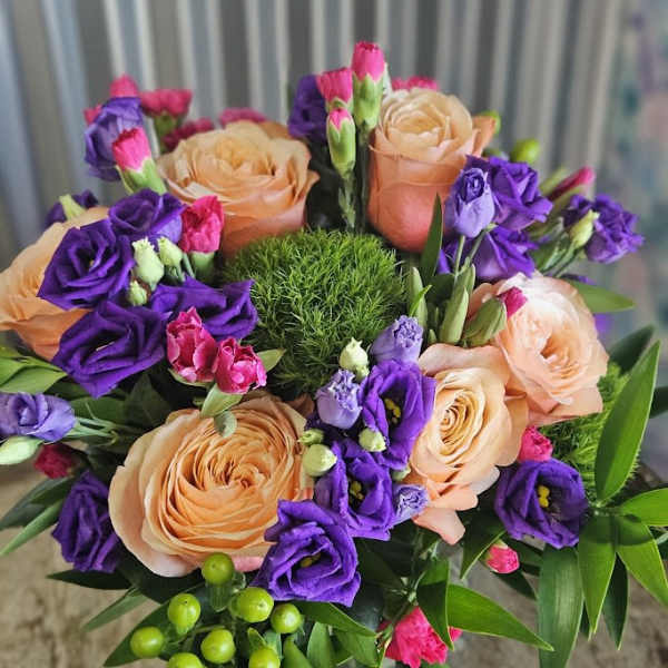 Peach roses and purple lisianthus in a round bouquet