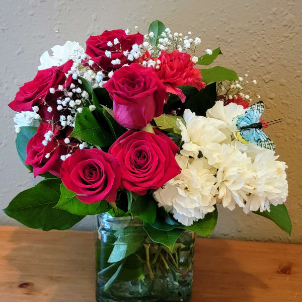 Bouquet of red roses and white carnations in a glass vase