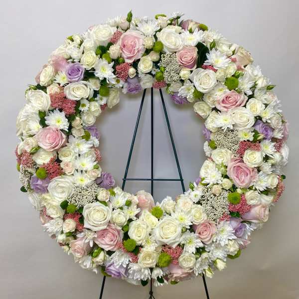 Large circular floral wreath of white, pink, and lavender blooms on an easel