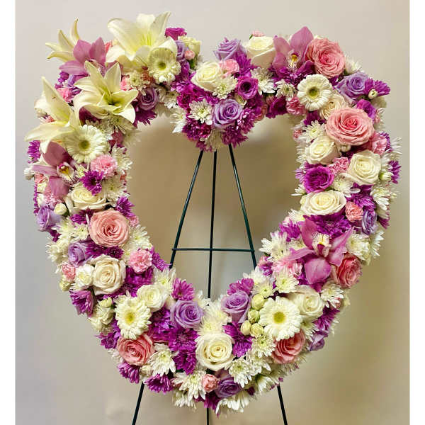 Heart-shaped floral wreath with pink, purple, and white flowers on a stand