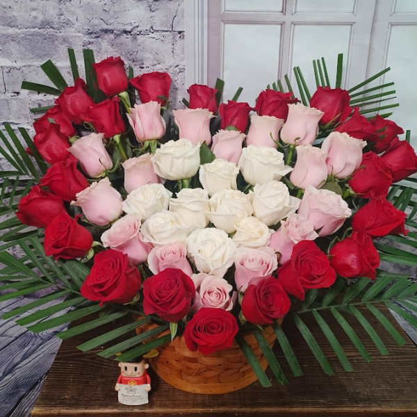 Heart-shaped bouquet of red, pink, and white roses in a basket
