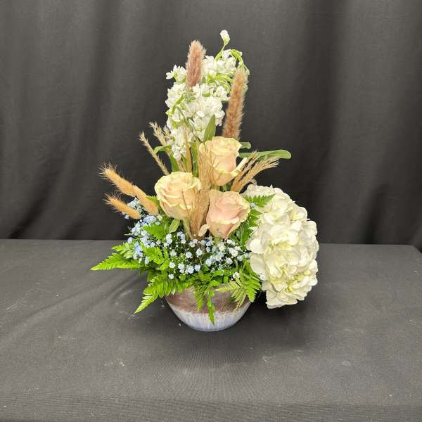 Cream roses and white hydrangeas in a low bowl arrangement