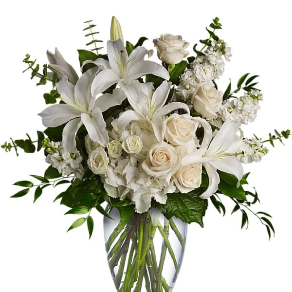 White lilies and roses arranged in a clear glass vase
