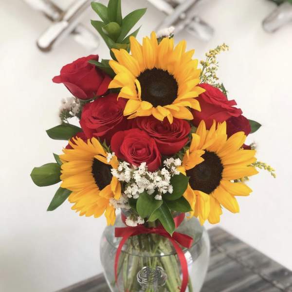 Bouquet of red roses and yellow sunflowers in a glass vase