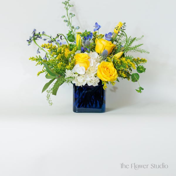 Yellow and blue floral arrangement in a dark blue vase