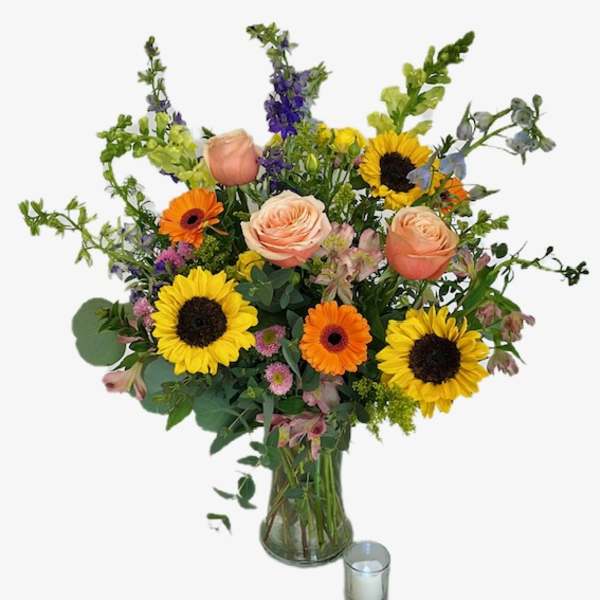 Mixed bouquet with sunflowers, roses, and gerbera daisies in a glass vase