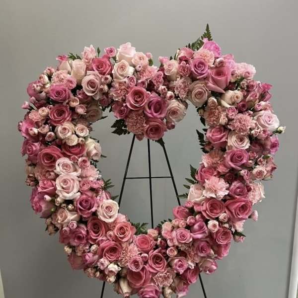 Heart-shaped floral wreath of pink and blush roses on a stand